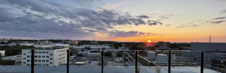 Sun setting over low rooftops, seen from a balcony